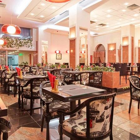 Elegante Restaurant mit stilvollen Tischen, dekoriert mit roten Blumen und sanfter Beleuchtung, die eine einladende Atmosphäre schafft.