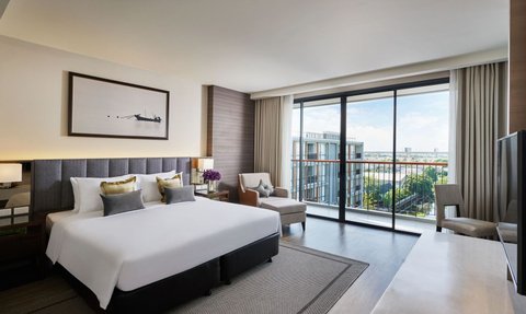 Ein modernes Hotelzimmer mit einem großen Bett, eleganten Kissen und einem Balkon mit Blick auf die Stadt.