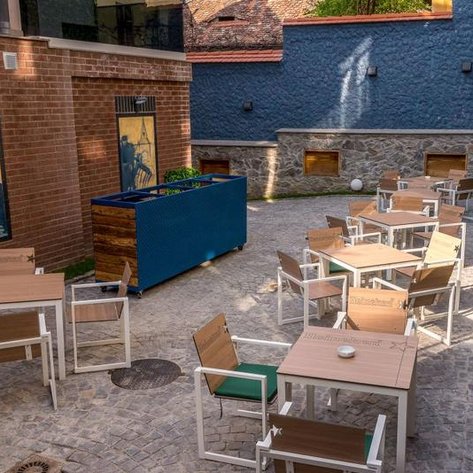 Eine einladende Terrasse mit mehreren Tischen und Stühlen, umgeben von einer charmanten Steinmauer und bunten Pflanzen.