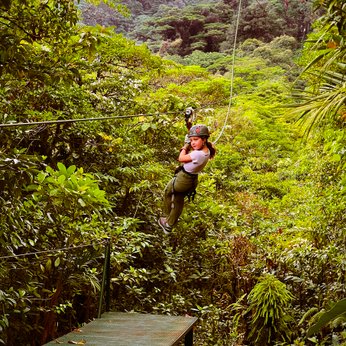 Mädchen gleitet lachend an einer Zipline durch den Dschungel bei einer Canopy-Tour – Costa Rica Familienreise