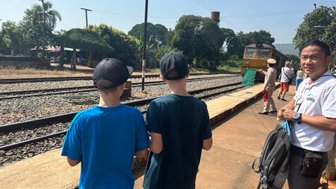 Guide und zwei Reisende Kinder beobachten die Einfahrt der Eisenbahn Death Train am Bahnsteg 