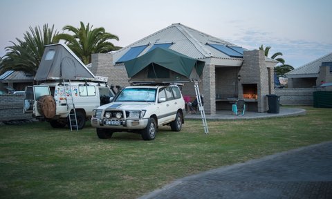 Campingbereich im Alte Brücke Resort mit Geländewagen, Dachzelten und Grillstelle vor den Bungalows - Namibia Familienreise