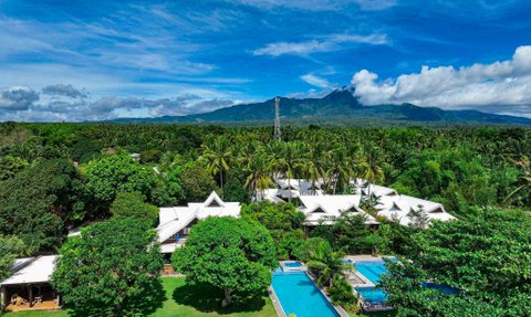 Eine expansive Aussicht auf ein tropisches Resort mit weißen Dächern, Pools und üppigem grünem Garten.