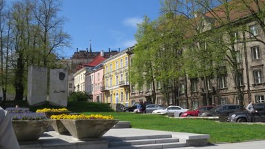 Eine sonnige Straße in Tallinn mit bunten Gebäuden und blühenden Blumenbeeten im Vordergrund.