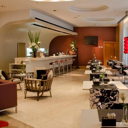 Ein eleganter Innenraum eines Cafés mit modernen Möbeln, hellen Farben und stilvollen Dekorationen, die eine einladende Atmosphäre schaffen.