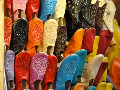 Farbenfrohe Schuhe aus Leder auf einem Marktstand im Bazar von Marrakesch – Marokko Reise mit Kindern