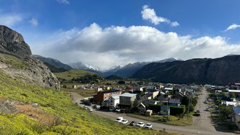 Eine malerische Ansicht von El Chaltén, umgeben von majestätischen Bergen und blühenden Wiesen im Vordergrund.