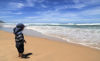 Kind steht an der Küste und blickt aufs Meer – Garden Route mit Kindern