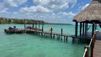 Kinder haben Spaß beim Sprung ins Wasser von einer Holzbrücke in der Lagune von Bacalar – Mexiko Reise mit Kindern