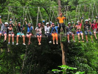 Teens sitzen auf einer Hängebrücke im Treetop Adventure Park in Kanchanaburi - Thailandreise mit Kindern