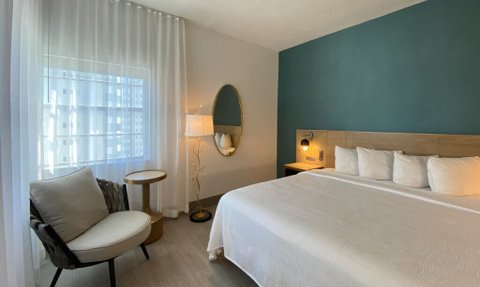 Helle und einladende hotellike Zimmer mit einem großen Bett, einem gemütlichen Sessel und einem eleganten Nachttisch.
