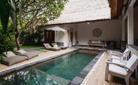 Ein eleganter Innenhof mit einem glitzernden Pool, umgeben von üppigem Grün und gemütlichen Liegen zum Entspannen.