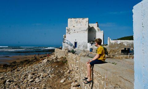 Kind genießt den Ausblick auf das Meer von einer Stadtmauer in Essaouira – Marokko Reise mit Kindern