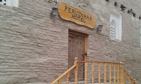 Der Eingang des Feruzkhan Hotels zeigt eine rustikale Holztreppe und eine kunstvoll gestaltete Tür.