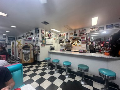 Ein nostalgisches Diner mit einer klassischen Jukebox und bunten Sitzbänken, geschmückt mit vielen Erinnerungsstücken.