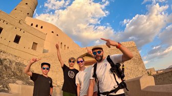 Familie macht Selfie mit Gebäude vom Bahla Fort im Oman – Oman Reise mit Kindern