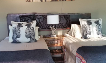 Zwei Einzelbetten in einem gemütlichen Schlafbereich, dekoriert mit Kissen und einem Nachttisch mit Lampe.