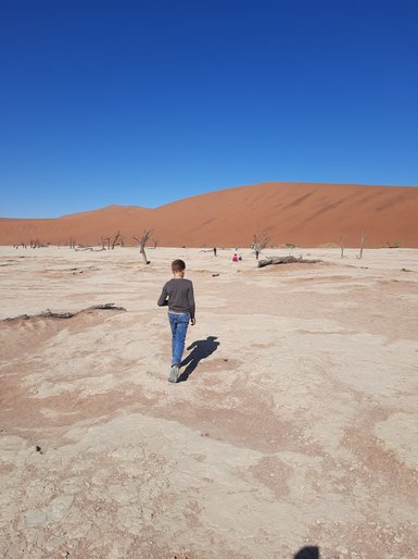 Ein Kind läuft durch eine Wüstenlandschaft - Namibia Reise mit Kindern