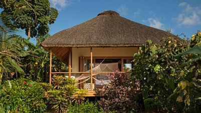 Ein charmantes, strohgedecktes Bungalow umgeben von üppigem Grün und bunten Blumen, ideal für einen entspannten Urlaub.