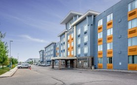 Das moderne Hotelgebäude in Calgary zeigt eine auffällige Fassade mit blauen und orangefarbenen Akzenten.