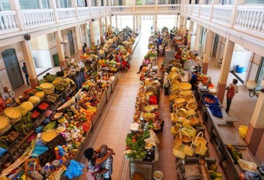 Der lebhafte Markt zeigt Stände voller frischer Früchte und Gemüse, umgeben von fröhlichen Händlern und Kunden.