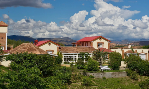 Eine malerische Lodge mit roten Dächern, umgeben von üppigem Grün und majestätischen Wolken am Himmel.