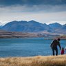 Eine Familie genießt einen sonnigen Tag am Wasser, während die Berge im Hintergrund majestätisch aufragen.