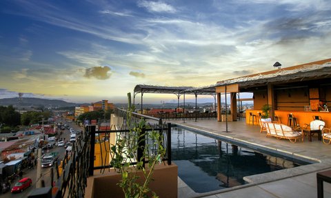 Der Blick von der Dachterrasse zeigt einen Pool und eine entspannte Atmosphäre mit Blick auf die Stadt und den Himmel.