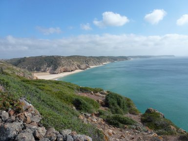 Eine atemberaubende Küstenlandschaft mit sanften Hügeln und klarem, blauem Wasser, das an einen goldenen Sandstrand plätschert.
