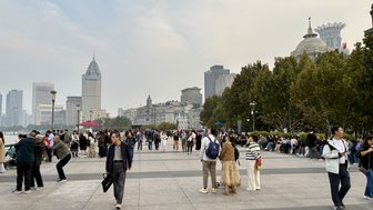 Eine belebte Promenade in Shanghai, gesäumt von Menschen, die die Aussicht auf die Stadt und den Fluss genießen.