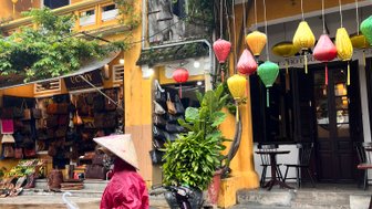 Frau trägt traditionellen vietnamesischen Hut bei Regen – Vietnam mit Kindern