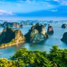 Eine atemberaubende Aussicht auf die Kalksteininseln von Ha Long Bay, umgeben von klarem, blauem Wasser und grünem Laub.