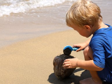 Kleines Kind spielt fröhlich im Sand am Strand – Costa Rica Familienreise