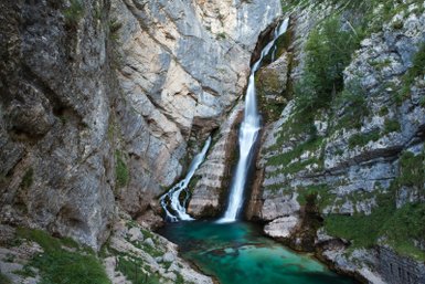 Ein majestätischer Wasserfall stürzt über steile Felsen in ein glasklares, türkisfarbenes Becken.