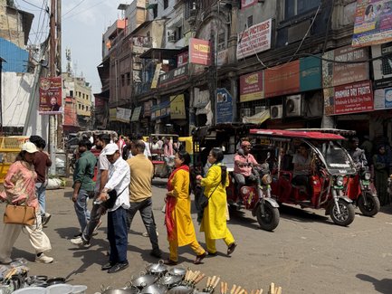Eine belebte Straße mit vielen Menschen, die an einem Markt mit Kochgeschirr und Töpfen vorbeigehen.