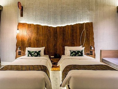 Zwei Einzelbetten mit eleganter Bettwäsche stehen in einem modernen Hotelzimmer mit Holzdetails und sanfter Beleuchtung.