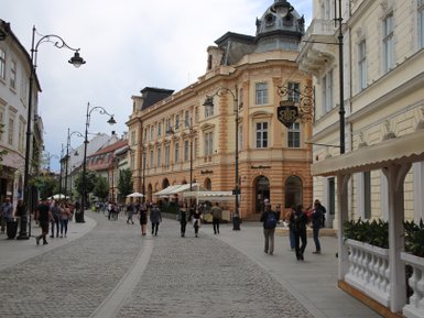 Eine belebte Straße in Sibiu, gesäumt von historischen Gebäuden und Menschen, die entspannt flanieren.