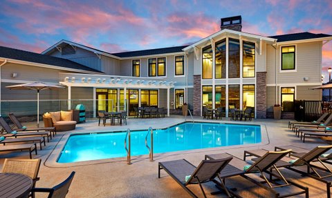 Ein einladender Poolbereich mit Liegen und einem modernen Gebäude im Hintergrund, beleuchtet von einem sanften Abendlicht.