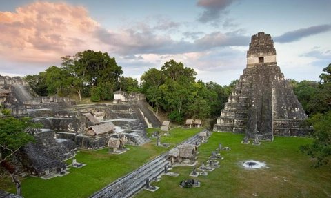 Die beeindruckenden Ruinen von Tikal zeigen eine große Pyramide, umgeben von üppigem Grün und einem dramatischen Himmel.