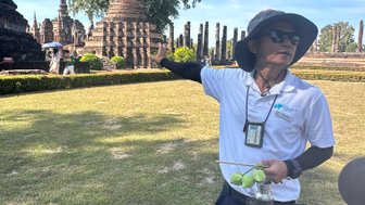 Lokaler Guide zeigt auf den Wat Mahathat Tempel in Sukhothai - Thailand Familienreise