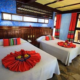 Zwei Einzelbetten mit bunten Kissen und dekorativen Bettüberwürfen in einem hellen, einladenden Raum.