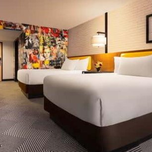 Ein modernes Hotelzimmer mit zwei großen Betten, bunten Wänden und einem stilvollen Teppichmuster.