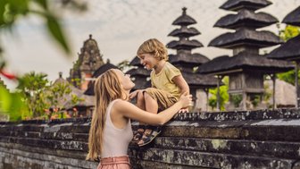 Mutter mit Kind beim Besuch eines balinesischen Tempels – Bali Familienreise