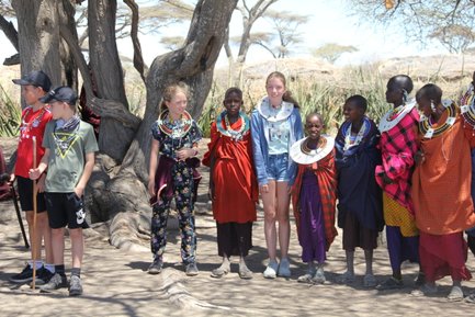 Kinder aus Reisegruppe posieren gemeinsam mit einer Massai-Familie – Tansania Familienreise