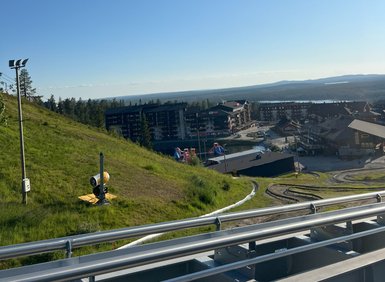 Eine grüne Hügellandschaft mit einem blauen Himmel und einem Blick auf ein Resort in der Ferne, ideal für Freizeitaktivitäten.
