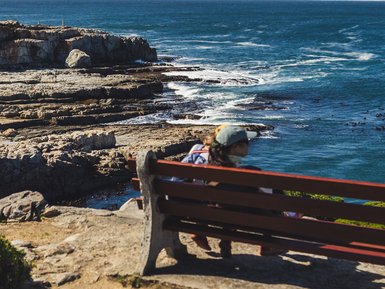 Kindern genießen die Aussicht auf einer Bank in Hermanus – Südafrika Familienreise