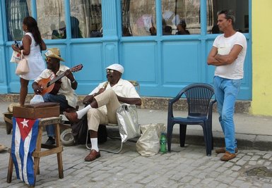 Zwei Musiker spielen auf der Straße, während ein Passant in lässiger Kleidung zuschaut. Die Umgebung ist farbenfroh und lebhaft.