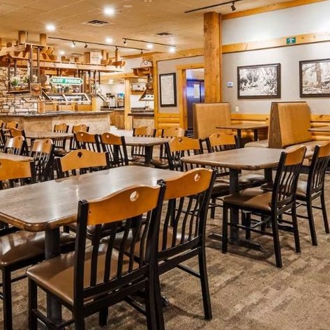 Ein einladendes Restaurant mit Holzmöbeln, leeren Tischen und Stühlen, das eine gemütliche Atmosphäre ausstrahlt.