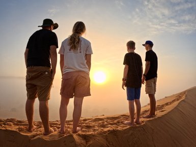 Familie genießt den Sonnenuntergang in der Sandwüste – Oman Familienreise