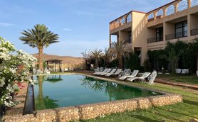 Ein klarer Pool spiegelt den Himmel und die umgebenden Palmen wider, während lounge-Bereiche einladend wirken.